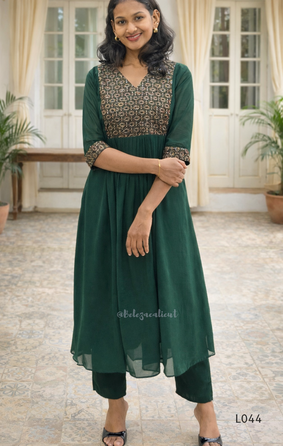 Woman wearing a green traditional outfit with a patterned top in an indoor setting.
