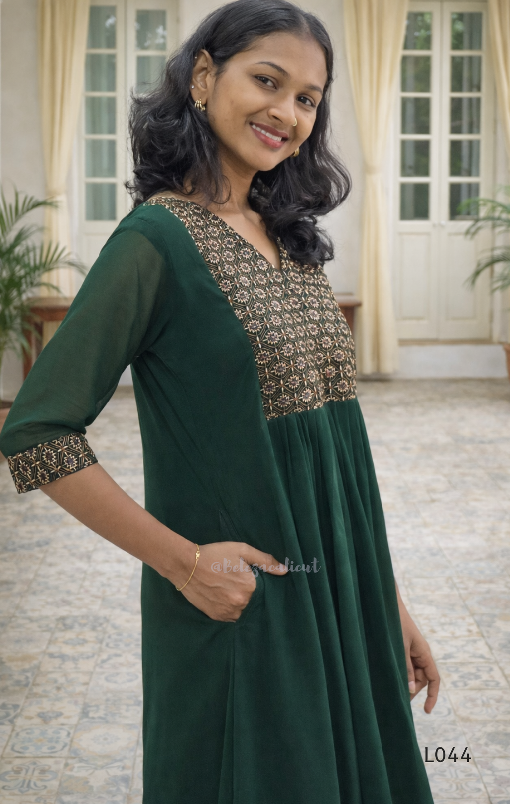 Woman wearing a green traditional outfit with floral patterns indoors.