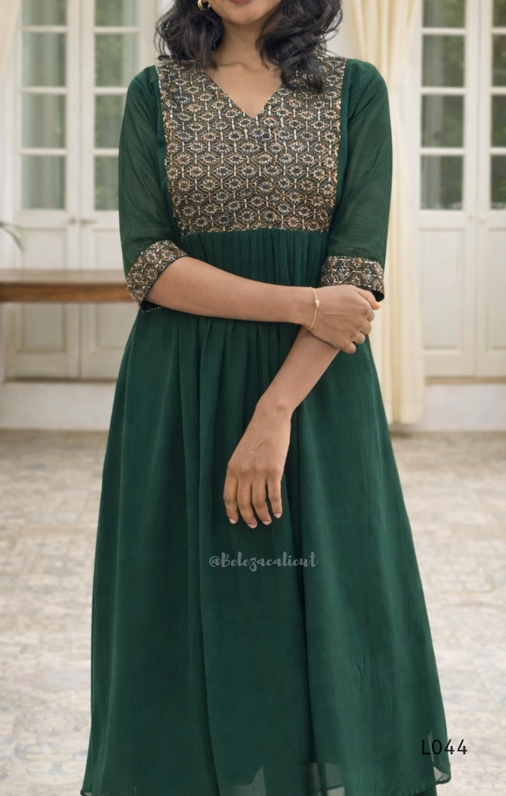 Woman wearing a green dress with patterned sleeves in an indoor setting