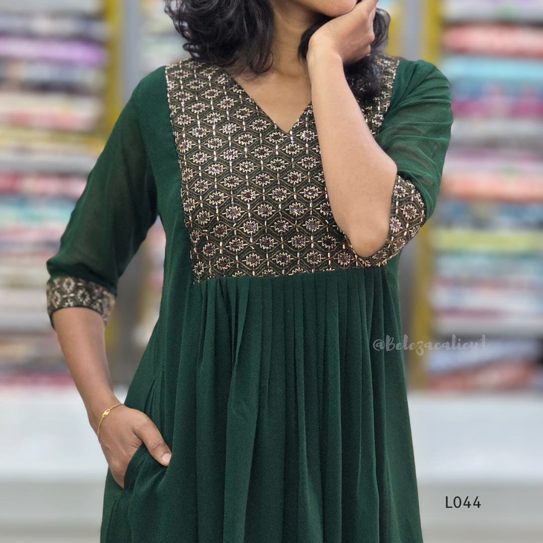 Green dress with patterned neckline worn by a person, blurred background