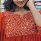 Close-up of a person wearing an orange embroidered traditional outfit.