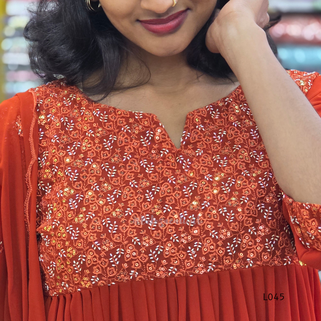 Close-up of a person wearing an orange embroidered traditional outfit.