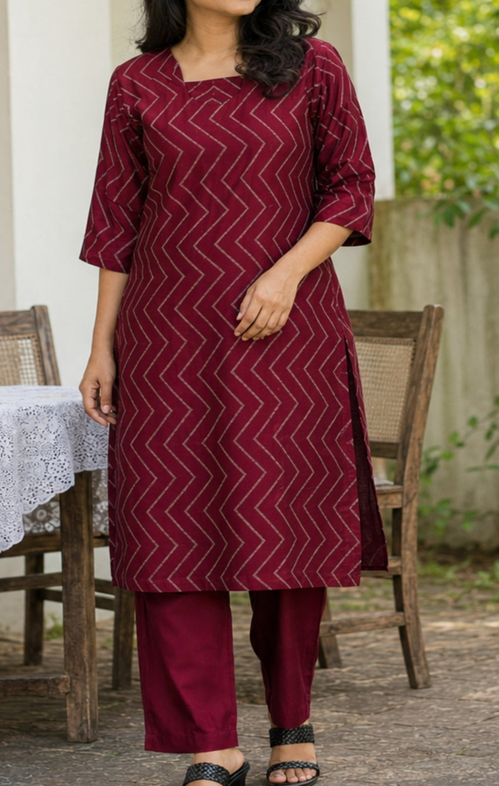 Woman wearing a maroon patterned kurta with pants in an outdoor setting.