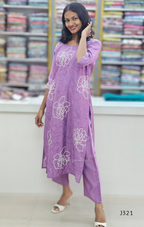 Woman wearing a purple dress with floral patterns in a fabric store.