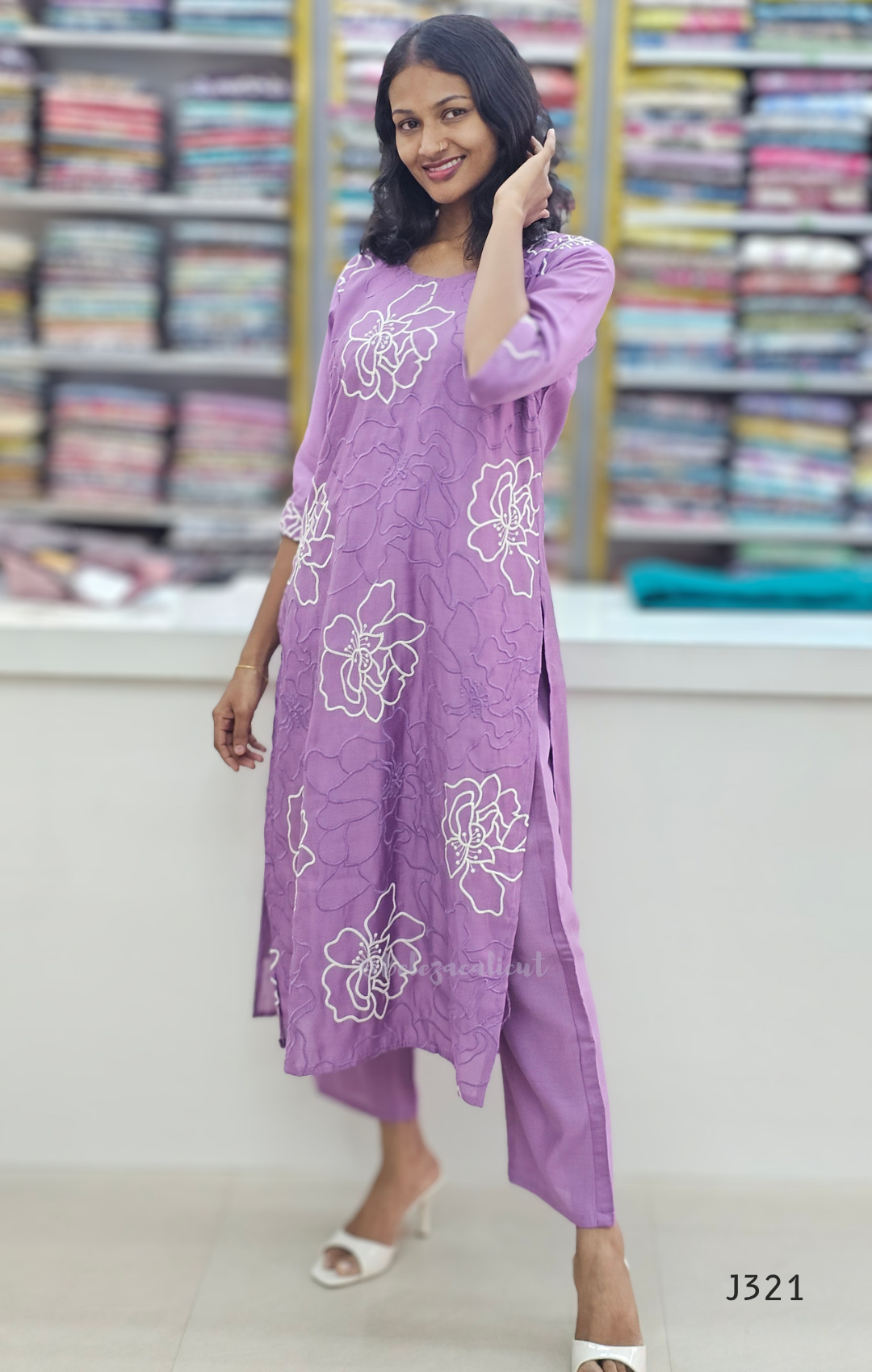 Woman wearing a purple dress with floral patterns in a fabric store.