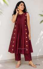 Deep maroon Vertigan silk co-ord set with pleated A-line top, gold circular side motifs and matching straight pants.
