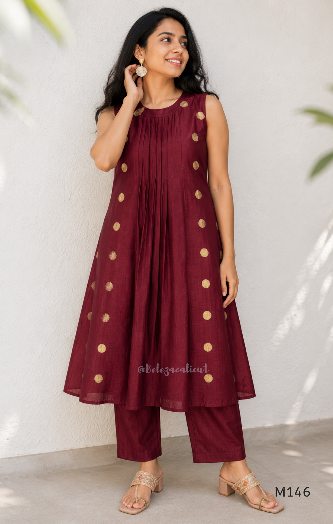 Deep maroon Vertigan silk co-ord set with pleated A-line top, gold circular side motifs and matching straight pants.
