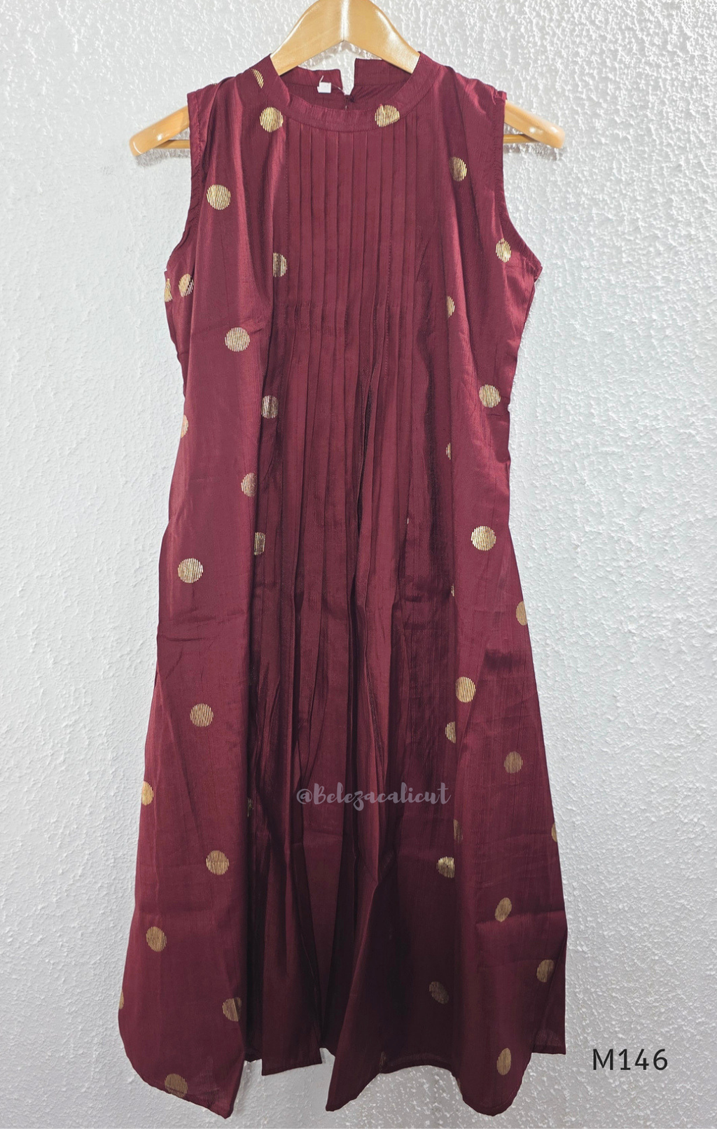 Deep maroon Vertigan silk co-ord set with pleated A-line top, gold circular side motifs and matching straight pants.