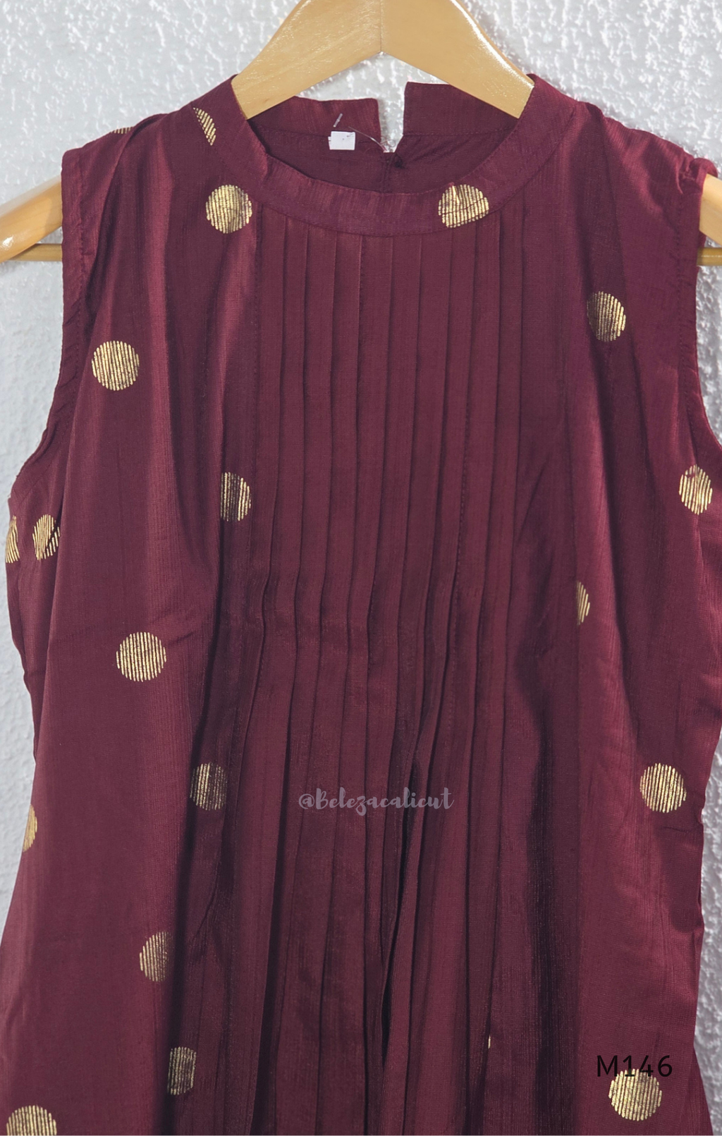 Deep maroon Vertigan silk co-ord set with pleated A-line top, gold circular side motifs and matching straight pants.