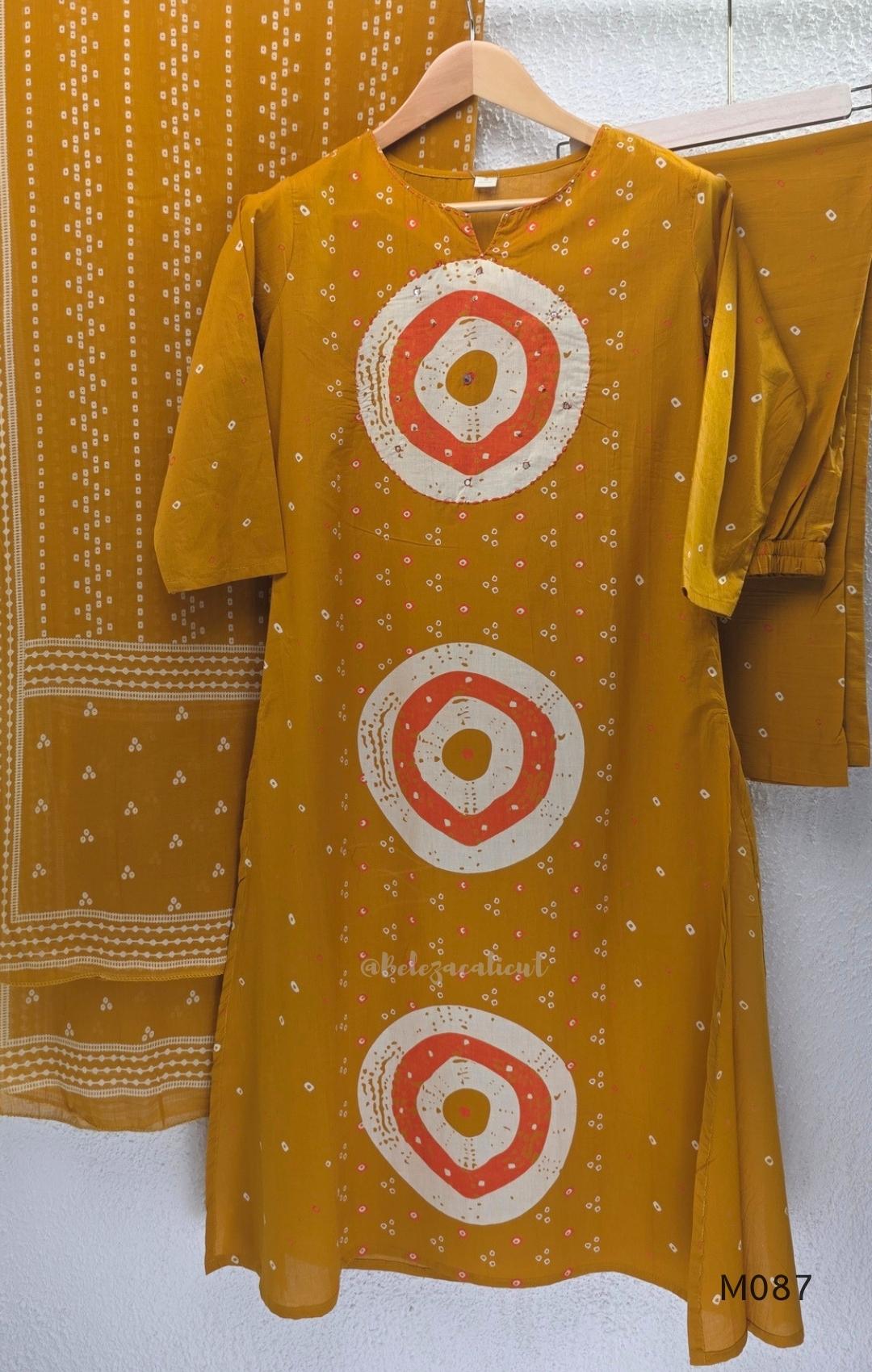 Mustard cotton 3-piece churidar set with abstract circle print kurta, matching printed dupatta and ankle-cuff bottom.