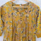 Mustard yellow silk blend 2-piece kurti set with floral print, gathered yoke, 3/4 sleeves, button detail, and matching bottom.