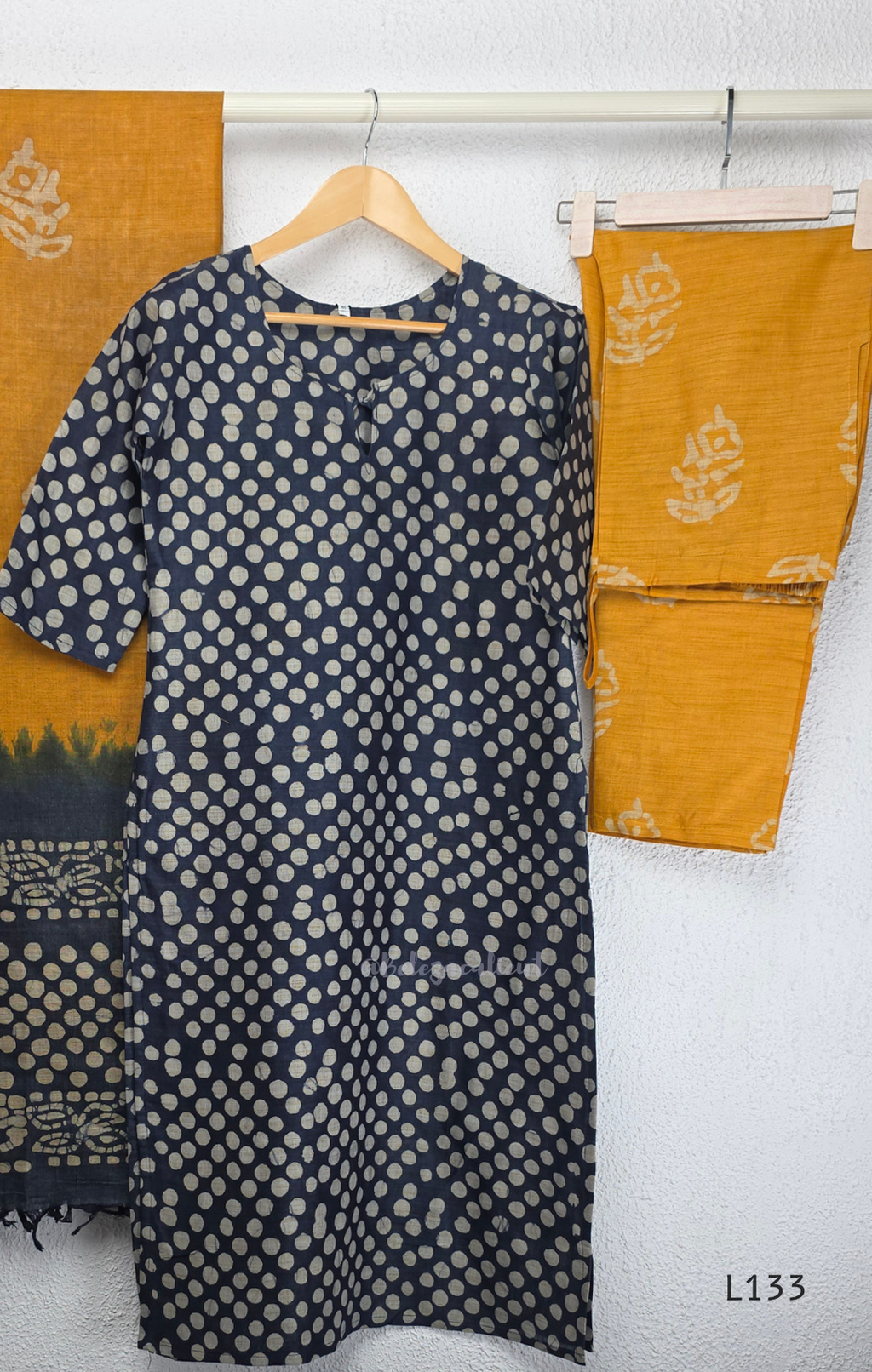 Navy blue chanderi silk churidar set with all-over cream polka dot block print, straight cut kurti with round neck and 3/4 sleeves, paired with plain mustard churidar bottom and mustard-navy dual-tone block print dupatta with tassel border, Indian ethnic wear from Beleza Calicut
