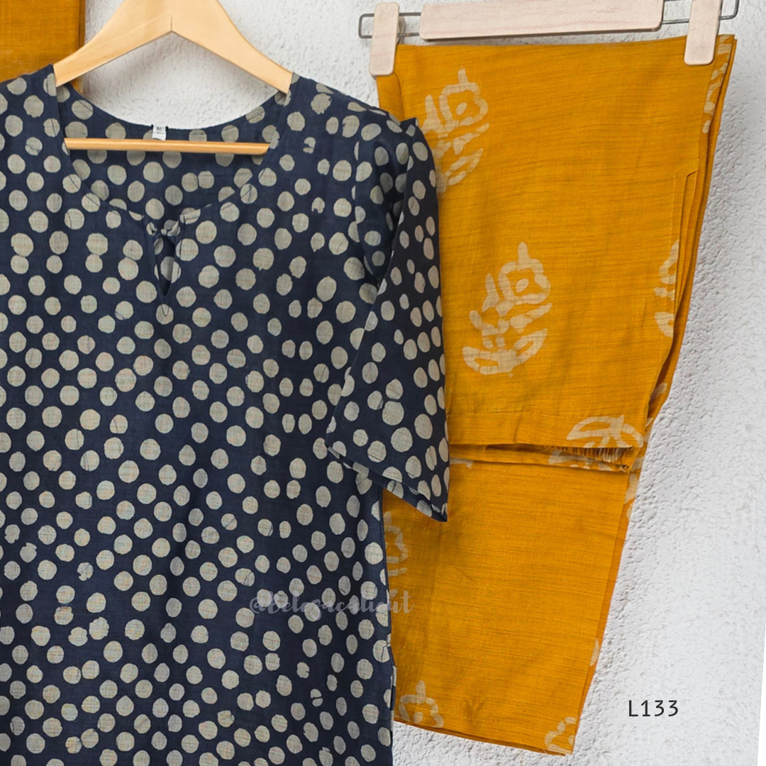 Navy blue chanderi silk churidar set with all-over cream polka dot block print, straight cut kurti with round neck and 3/4 sleeves, paired with plain mustard churidar bottom and mustard-navy dual-tone block print dupatta with tassel border, Indian ethnic wear from Beleza Calicut