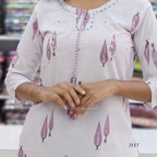 Off white cotton 2-piece kurti set with lavender leaf print, striped bottom, 3/4 sleeves, and tassel neckline worn by model.