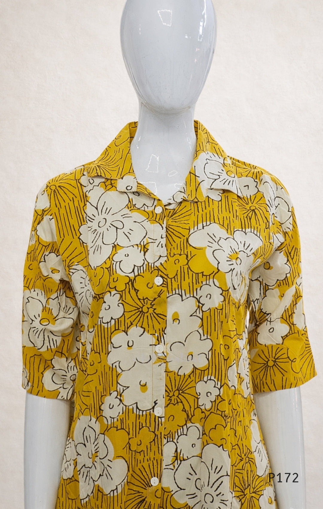 Yellow floral shirt on a mannequin against a white background