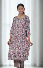 Woman wearing a patterned kurta with white curtains in the background