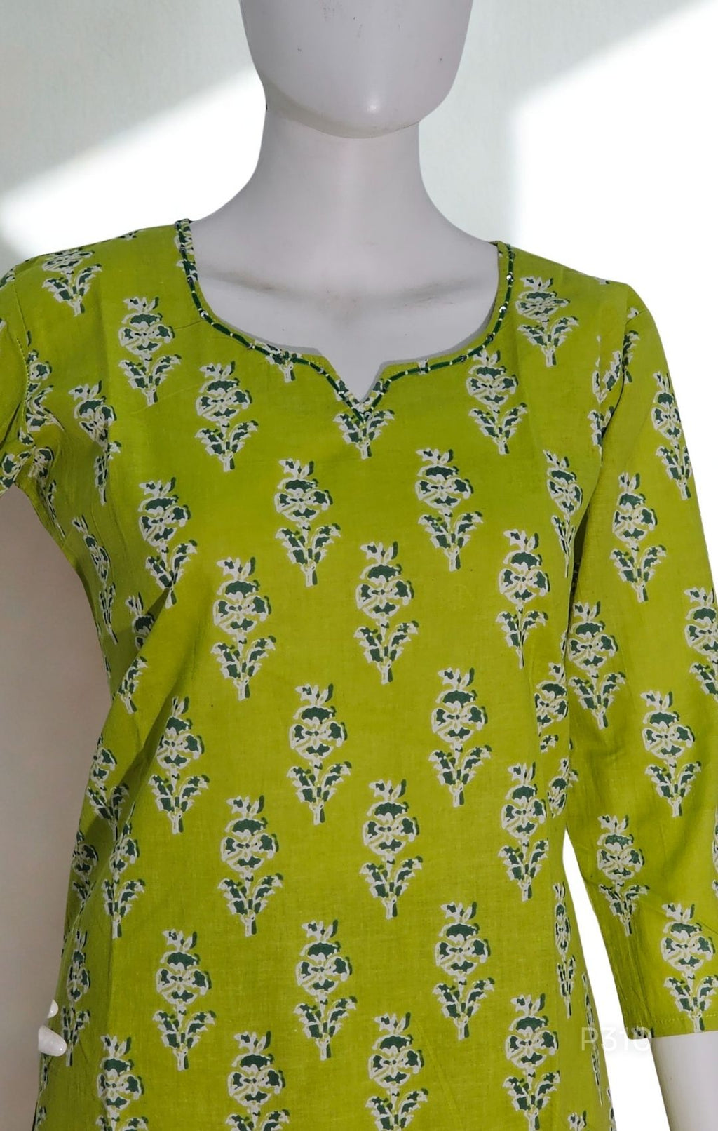 Green patterned top on a mannequin against a white background
