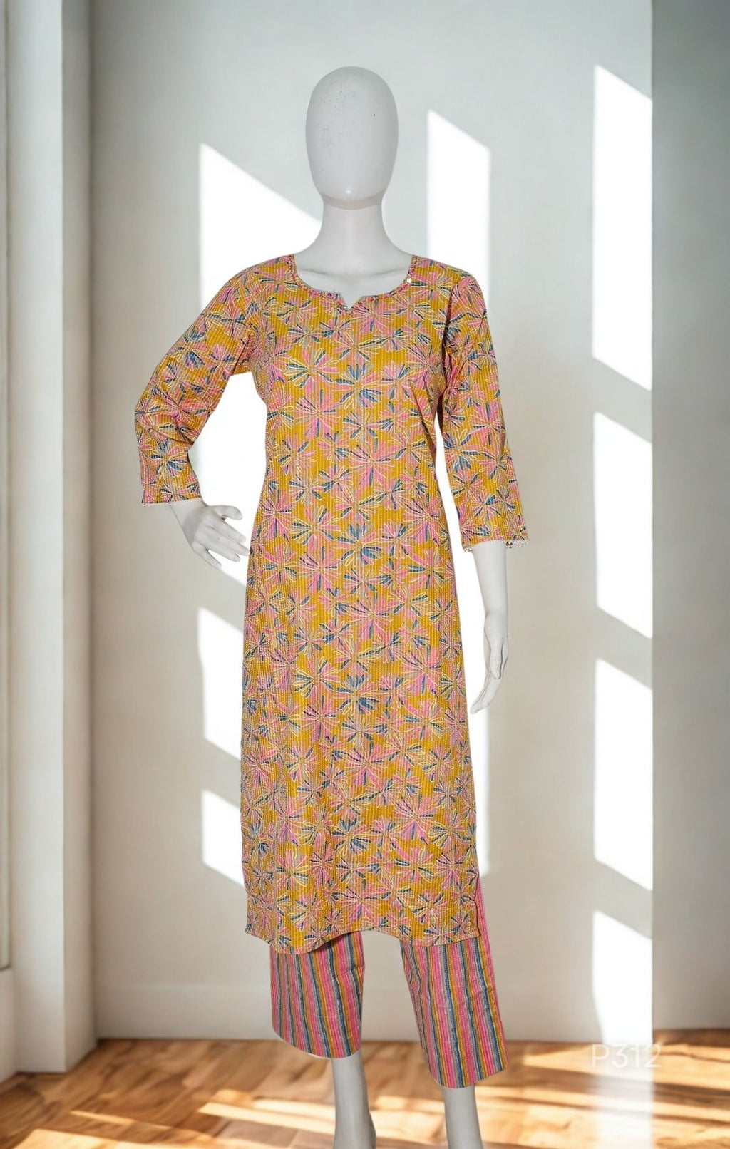 Mannequin wearing a patterned kurta with pants in a bright room.