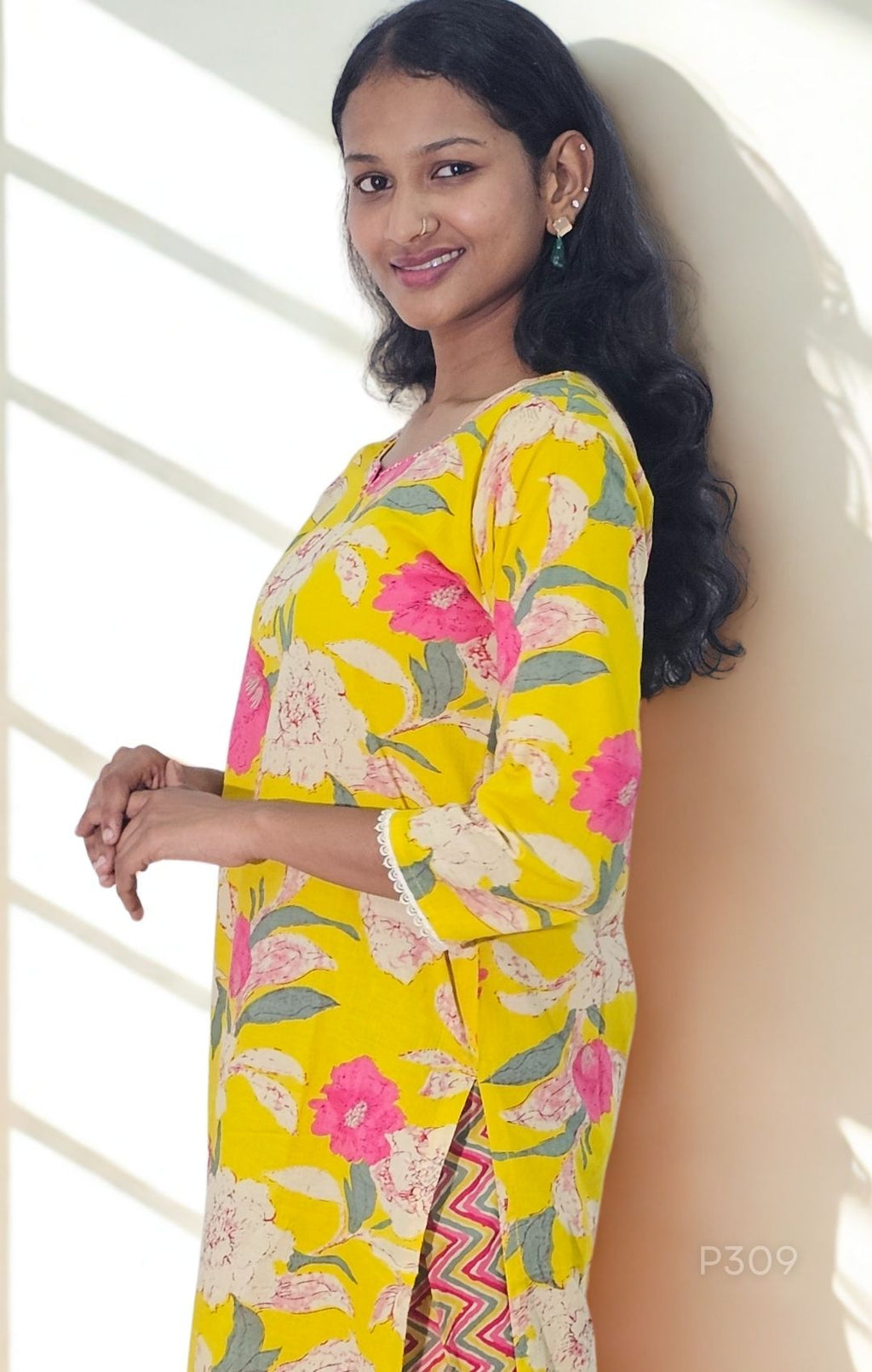 Woman wearing a yellow floral dress against a white background