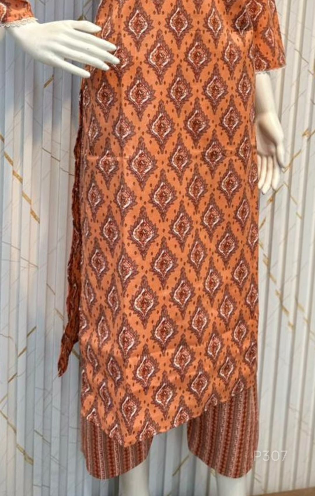 Orange patterned kurta with matching pants on a mannequin against a white background