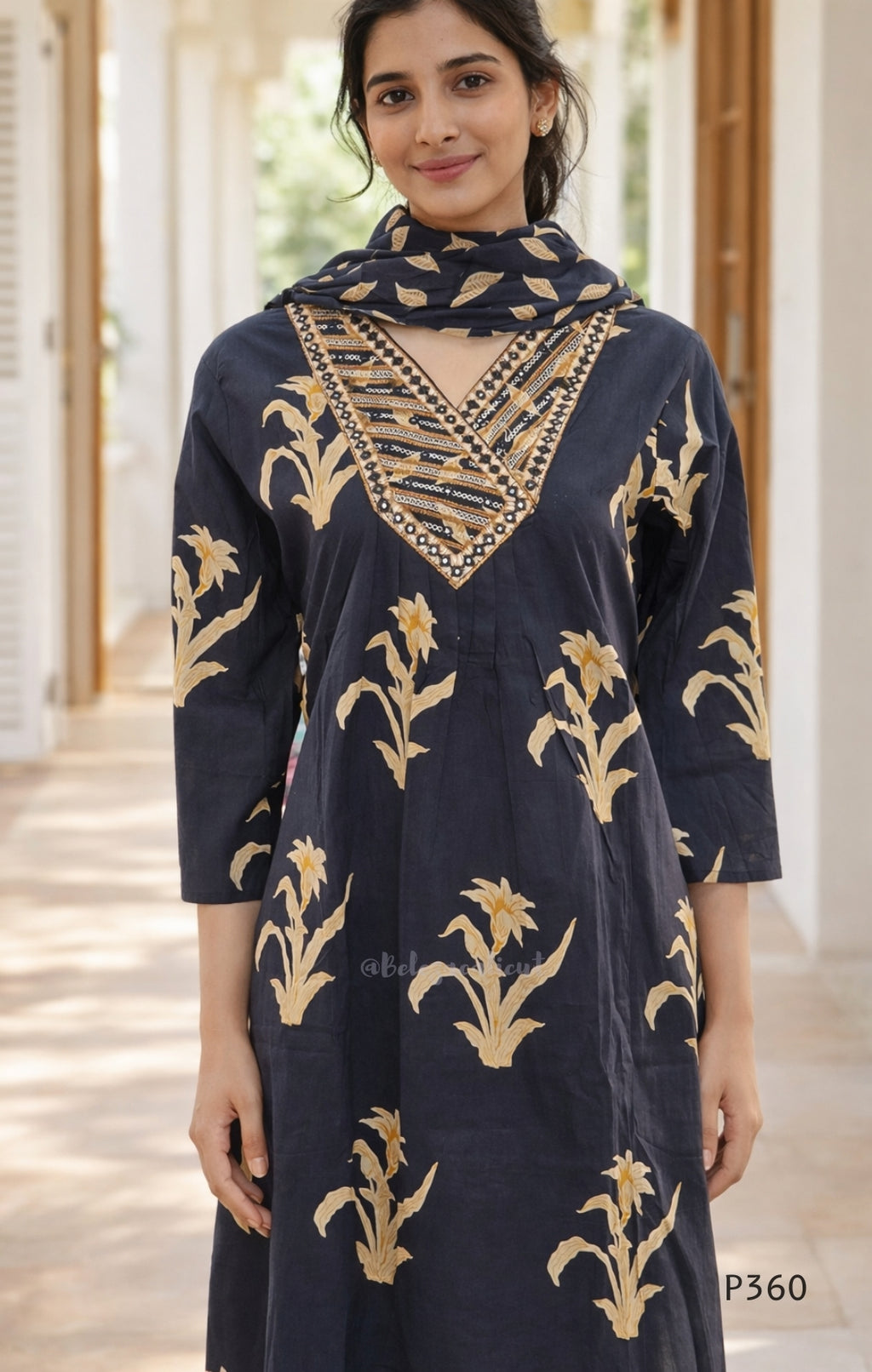 Woman wearing a black dress with gold floral patterns and embellishments.