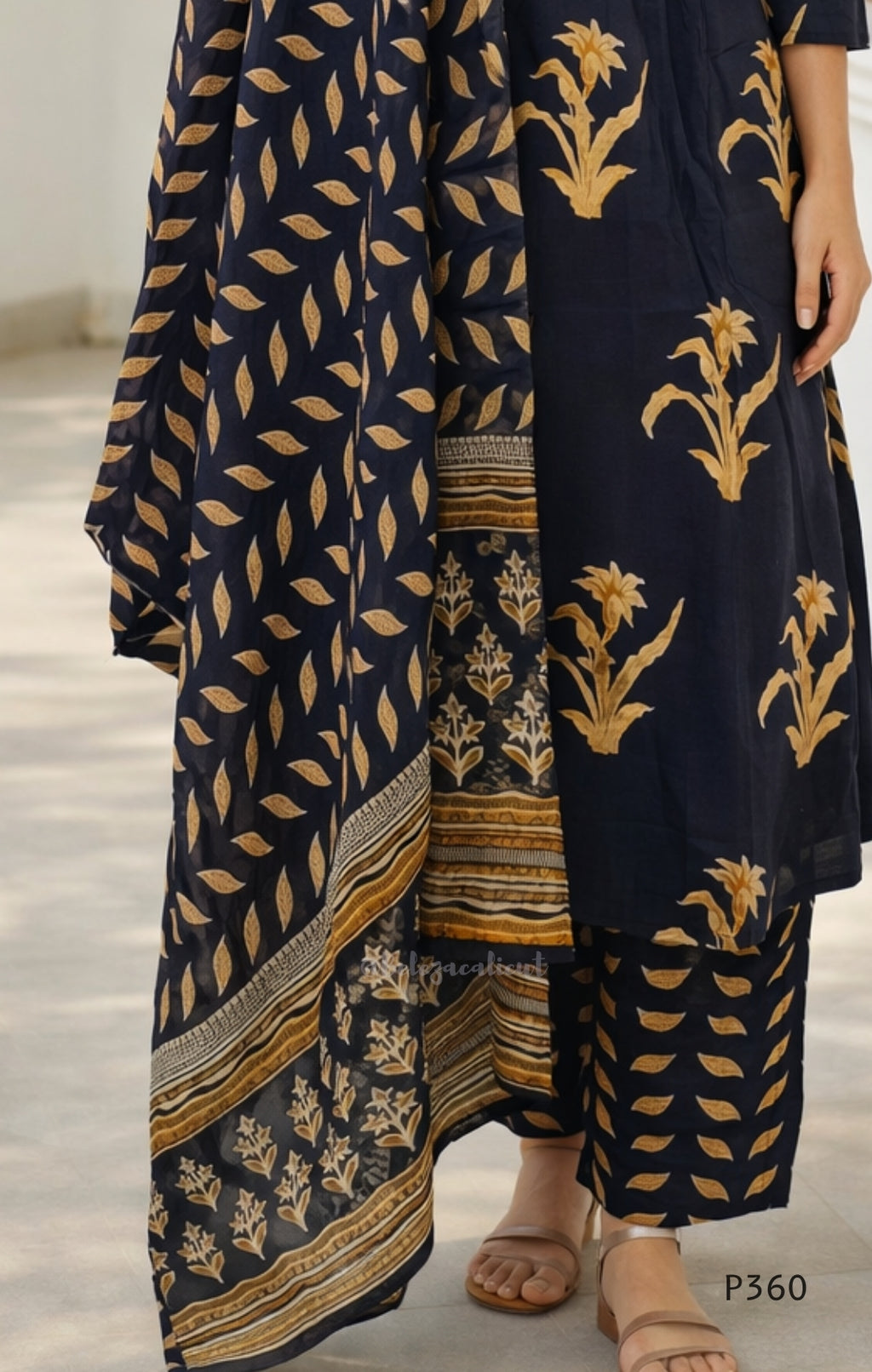 black traditional outfit with gold leaf patterns on a neutral background