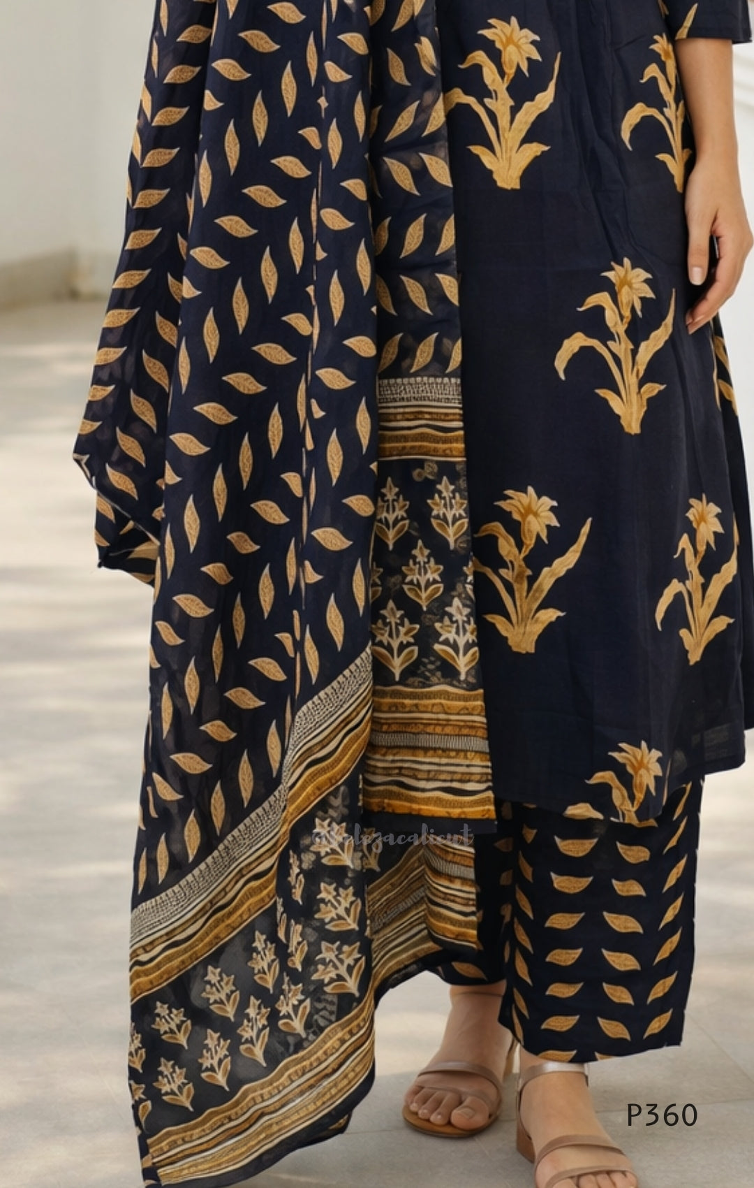 black traditional outfit with gold leaf patterns on a neutral background
