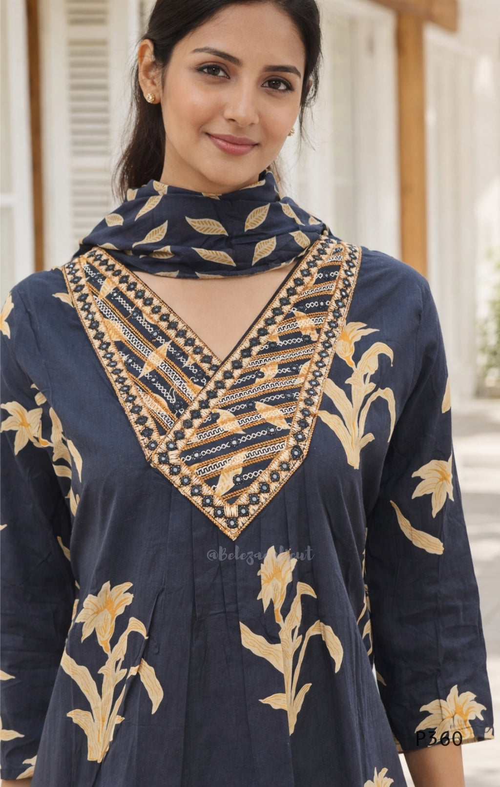Woman wearing a black embroidered dress with gold patterns
