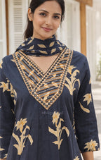Woman wearing a black embroidered dress with gold patterns