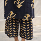 black outfit with gold floral patterns on a neutral background