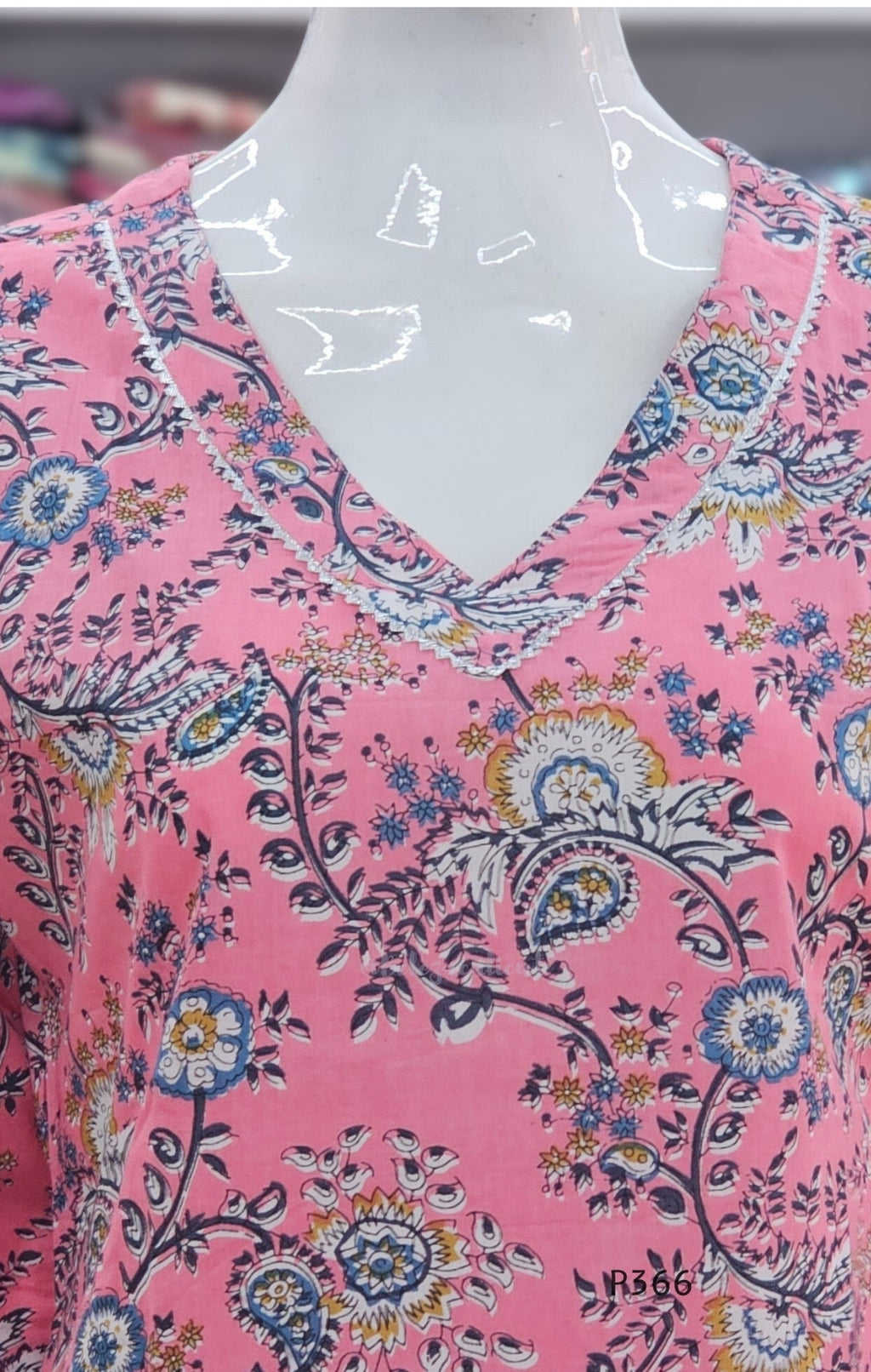 Mannequin wearing a pink floral patterned top with a blurred background