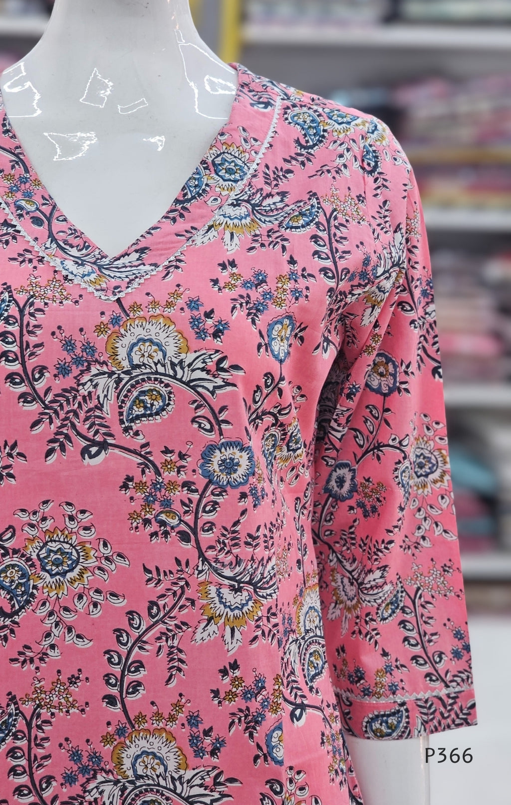 Pink floral patterned shirt on a mannequin with a blurred store background
