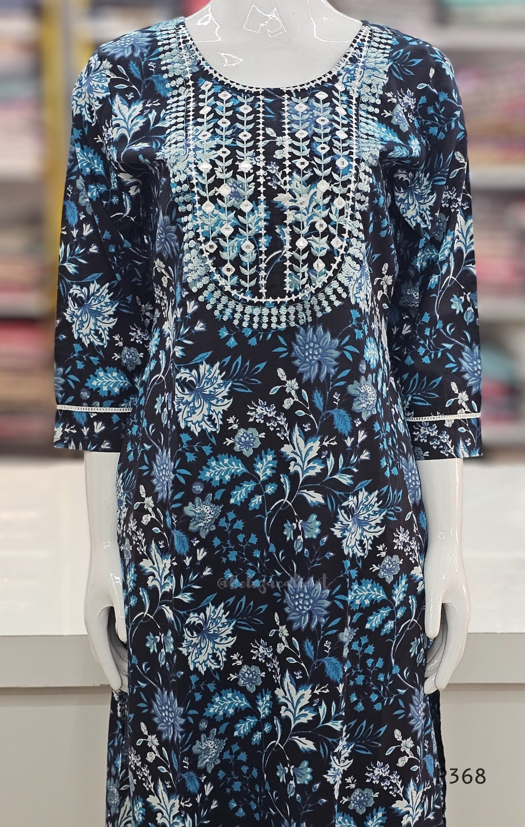 Floral dress with blue and white patterns on a mannequin against a blurred background