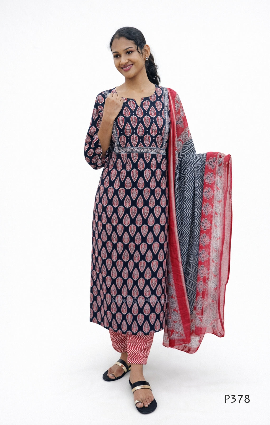 Woman wearing a navy blue and pink traditional outfit with a red dupatta on a white background