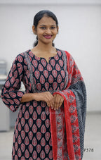 Woman wearing a black and red patterned kurta with a red dupatta against a white background