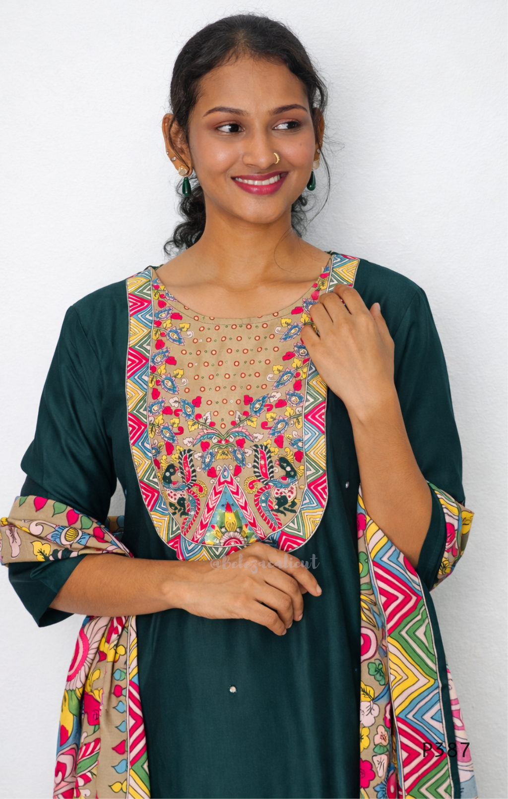 Woman wearing a green dress with colorful patterned sleeves and neckline against a white background