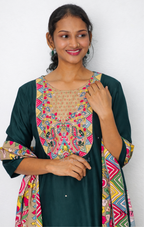 Woman wearing a green dress with colorful patterned sleeves and neckline against a white background
