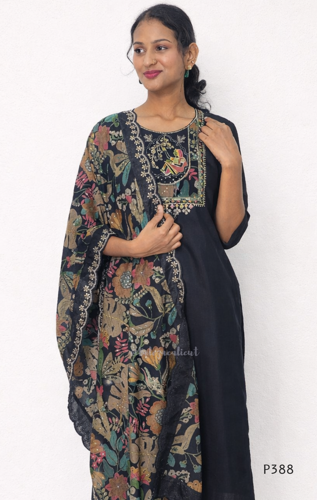 Woman wearing a black floral kurta with a patterned dupatta against a white background