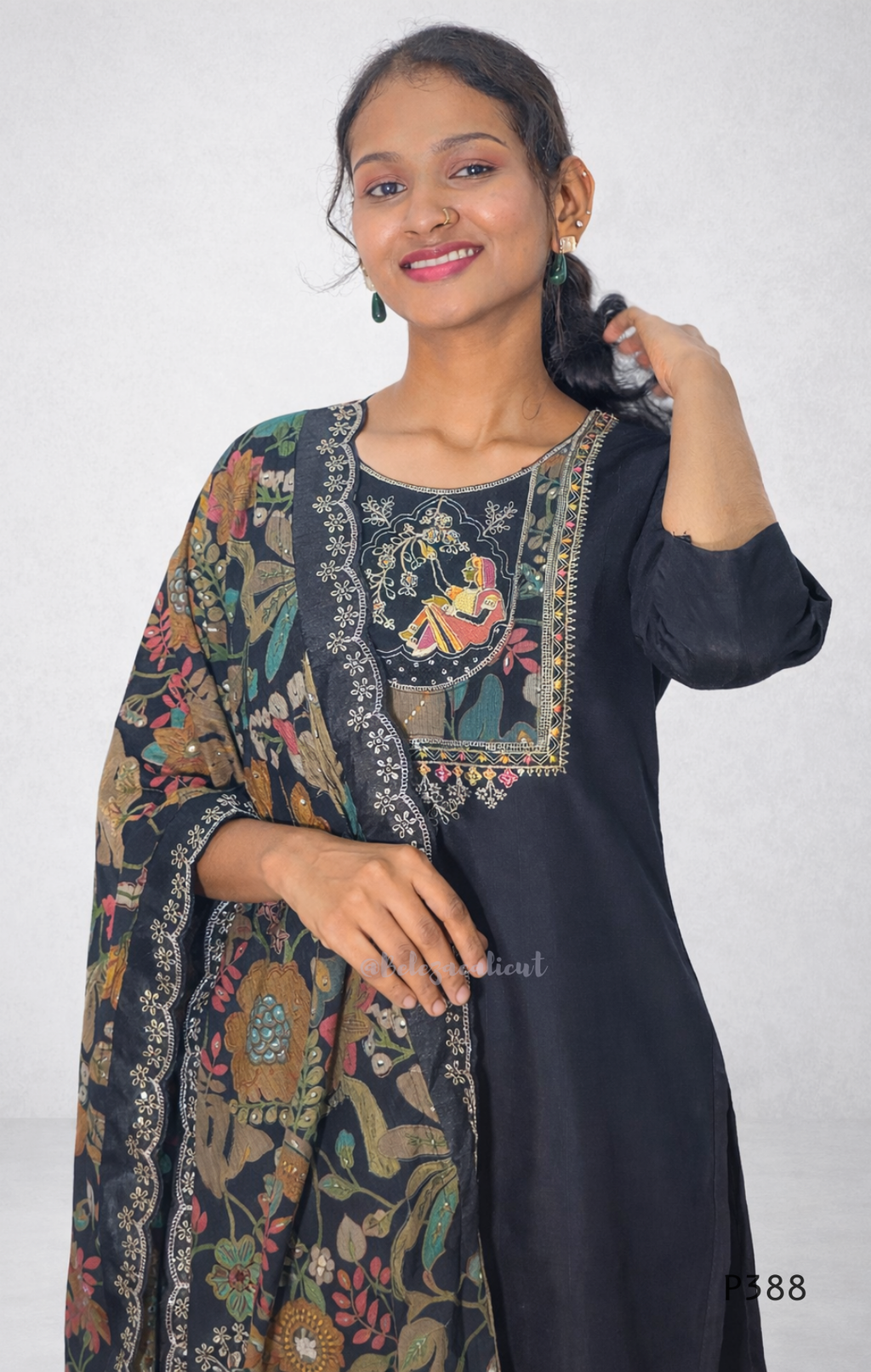 Woman wearing a black kurta with floral embroidery against a white background