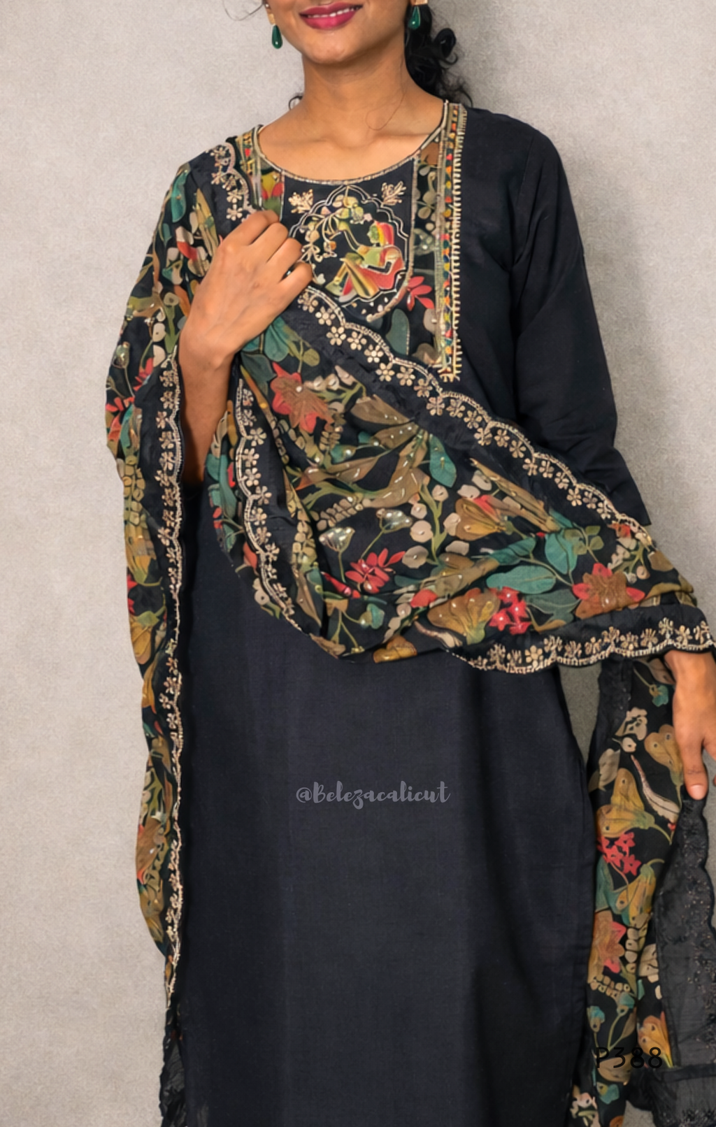 Woman wearing a black outfit with a floral embroidered dupatta against a plain background