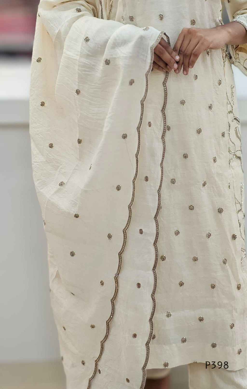 Beige traditional outfit with intricate detailing on a neutral background