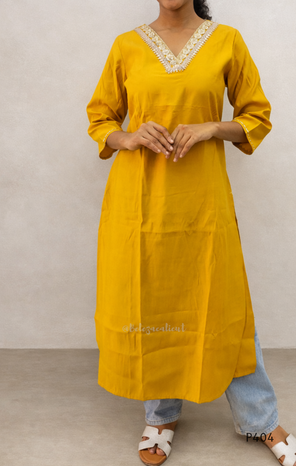 Person wearing a yellow kurta with white embroidery against a plain background