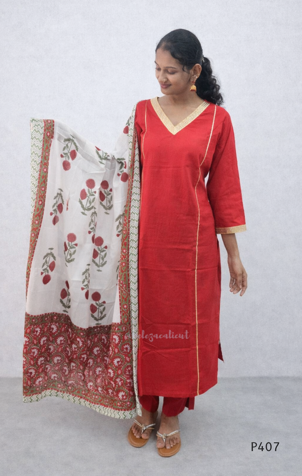 Woman wearing a red kurta with a white dupatta featuring floral patterns on a plain background