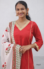 Woman wearing a red kurta with a white saree featuring red patterns on a plain background