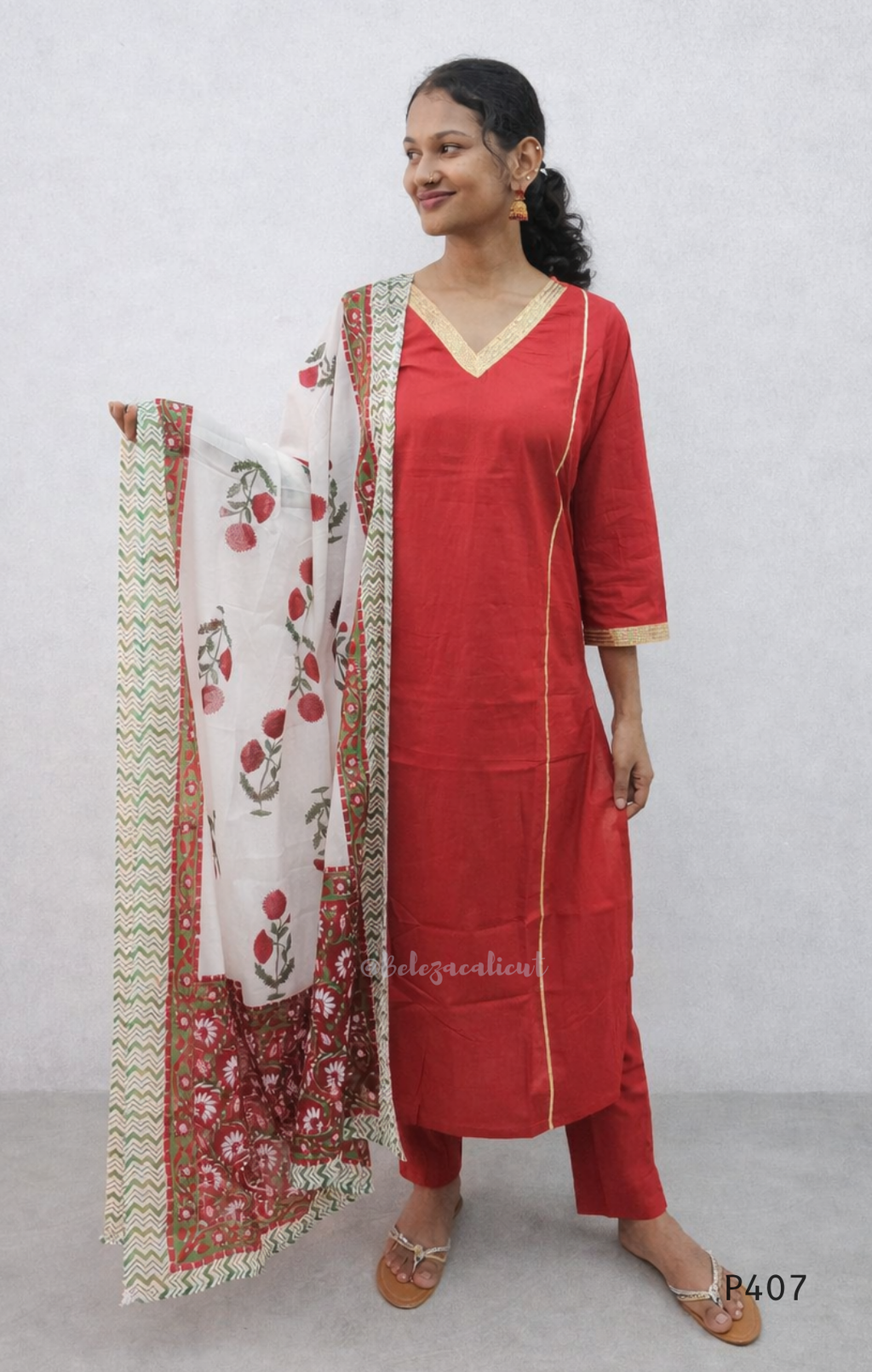 Woman wearing a red kurta with a matching dupatta against a white background
