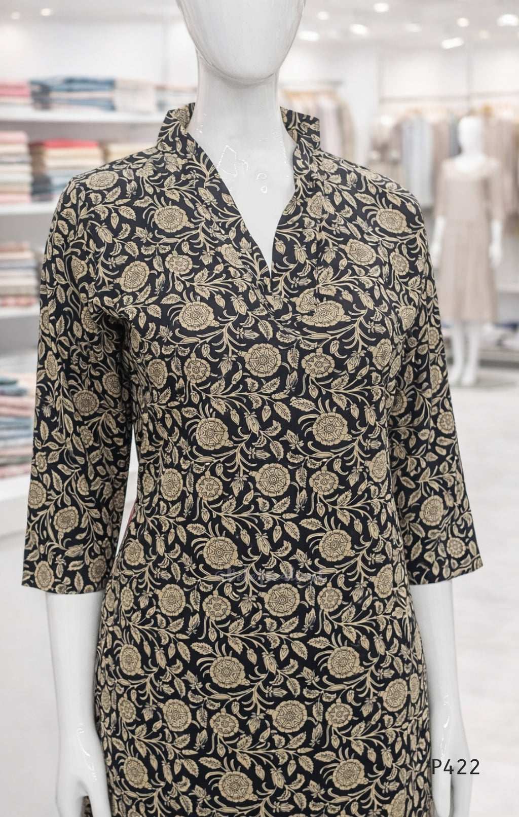 Mannequin wearing a black dress with gold floral pattern in a store setting