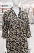 Mannequin wearing a black dress with gold floral pattern in a store setting