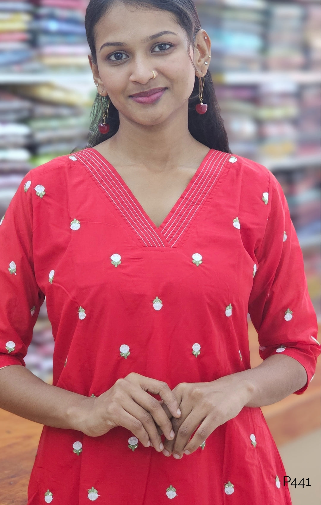 Woman wearing a red dress with white patterns in a store setting