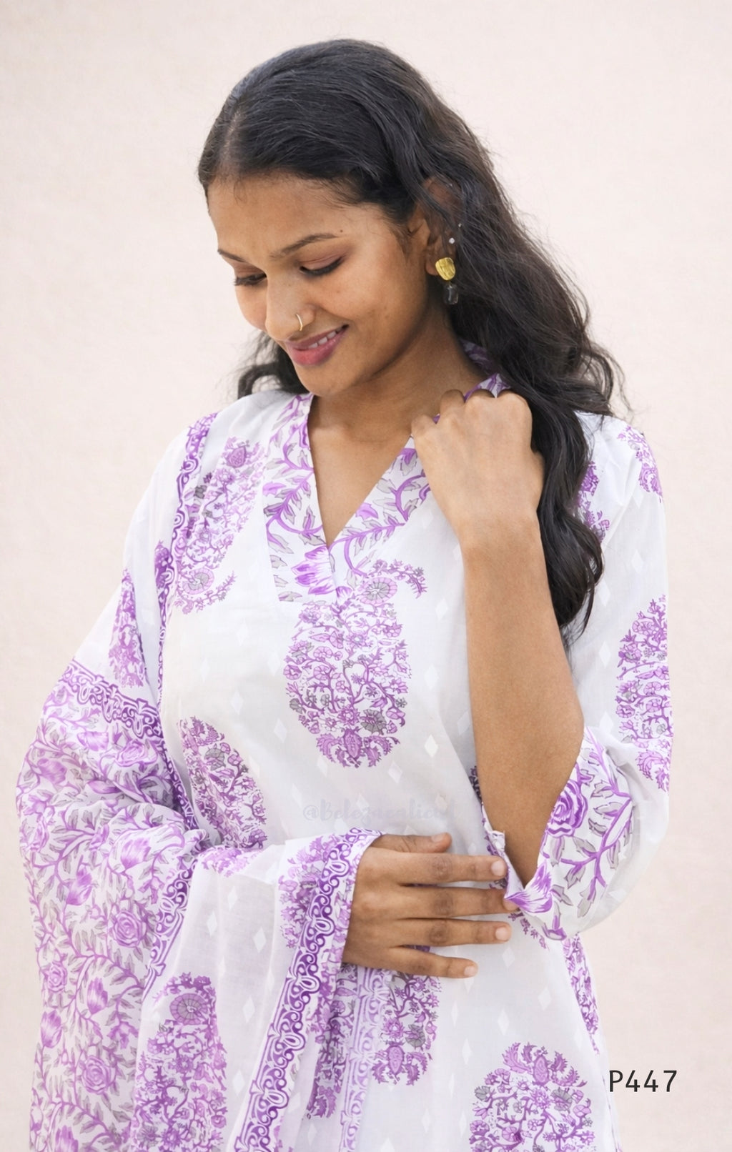 Woman wearing a white and purple floral dress against a plain background