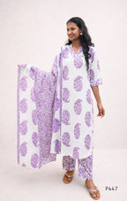 Woman wearing a white outfit with purple floral patterns on a plain background